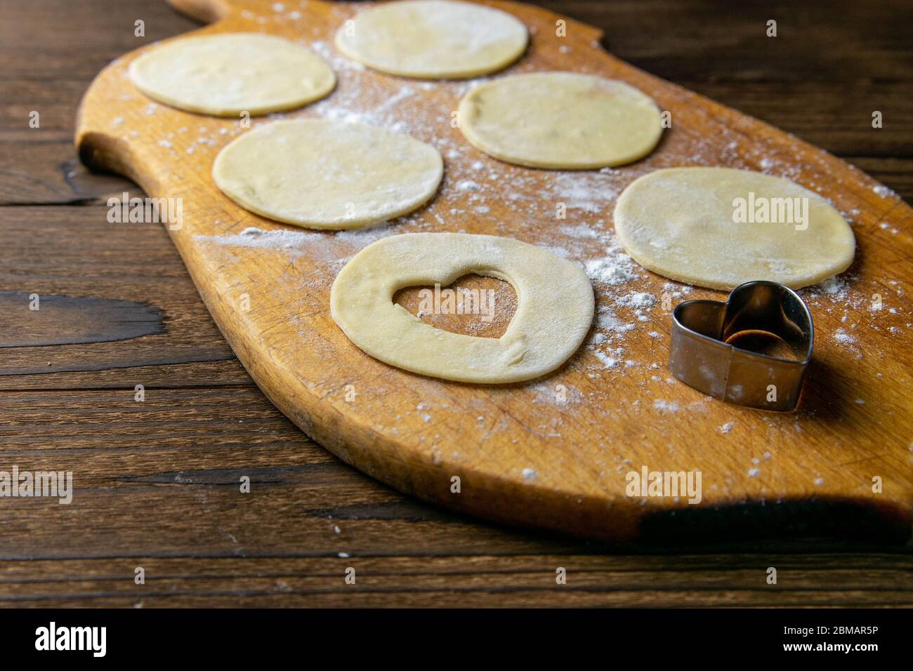 Gnocchi a forma di cuore, farina su fondo in legno. Cottura gnocchi. Vista frontale, primo piano Foto Stock