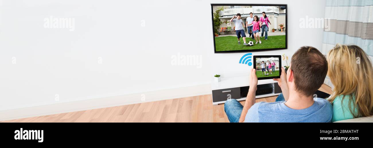 Tablet collegato al televisore. Persone che guardano e guardano in streaming Foto Stock