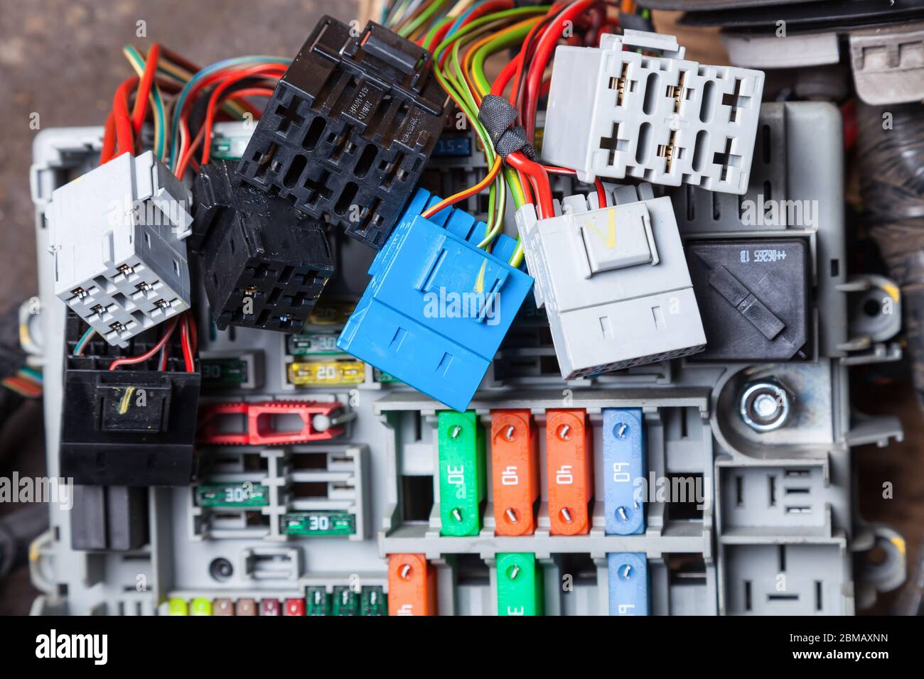 Fili elettrici multicolore - giallo verde e rosso con connettori in grigio blu e nero e con scatole fusibili sul pannello con supporti per il rappresentante dell'auto Foto Stock