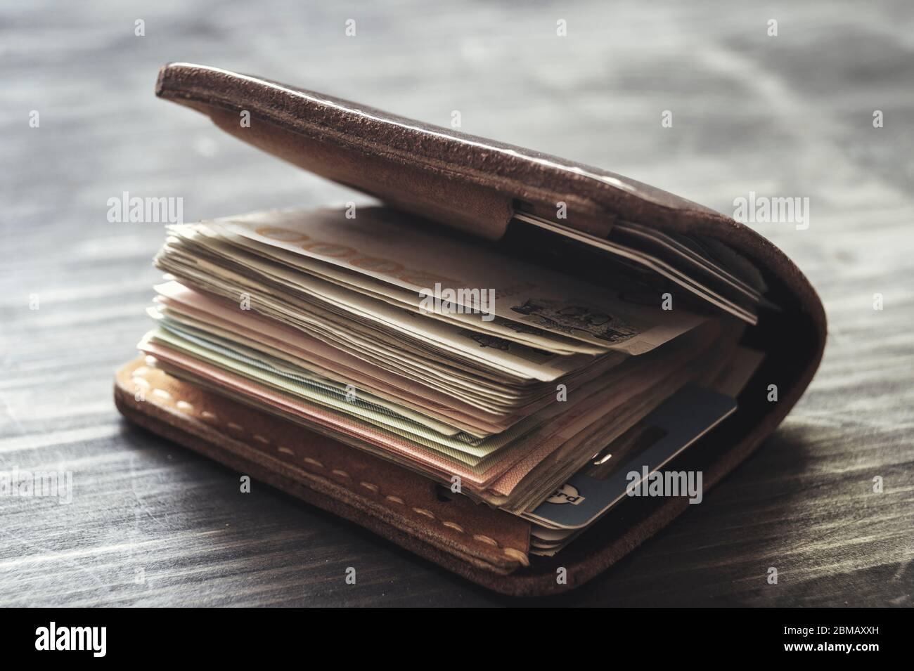 Portafoglio in pelle vecchio pieno di soldi su sfondo di legno, primo piano  Foto stock - Alamy