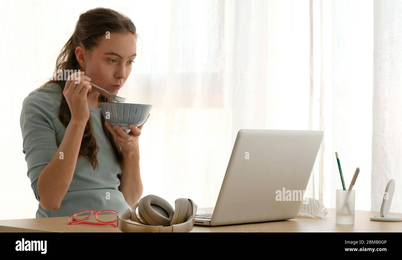 Giovane donna che mangia porridge a tavola in soggiorno Foto Stock