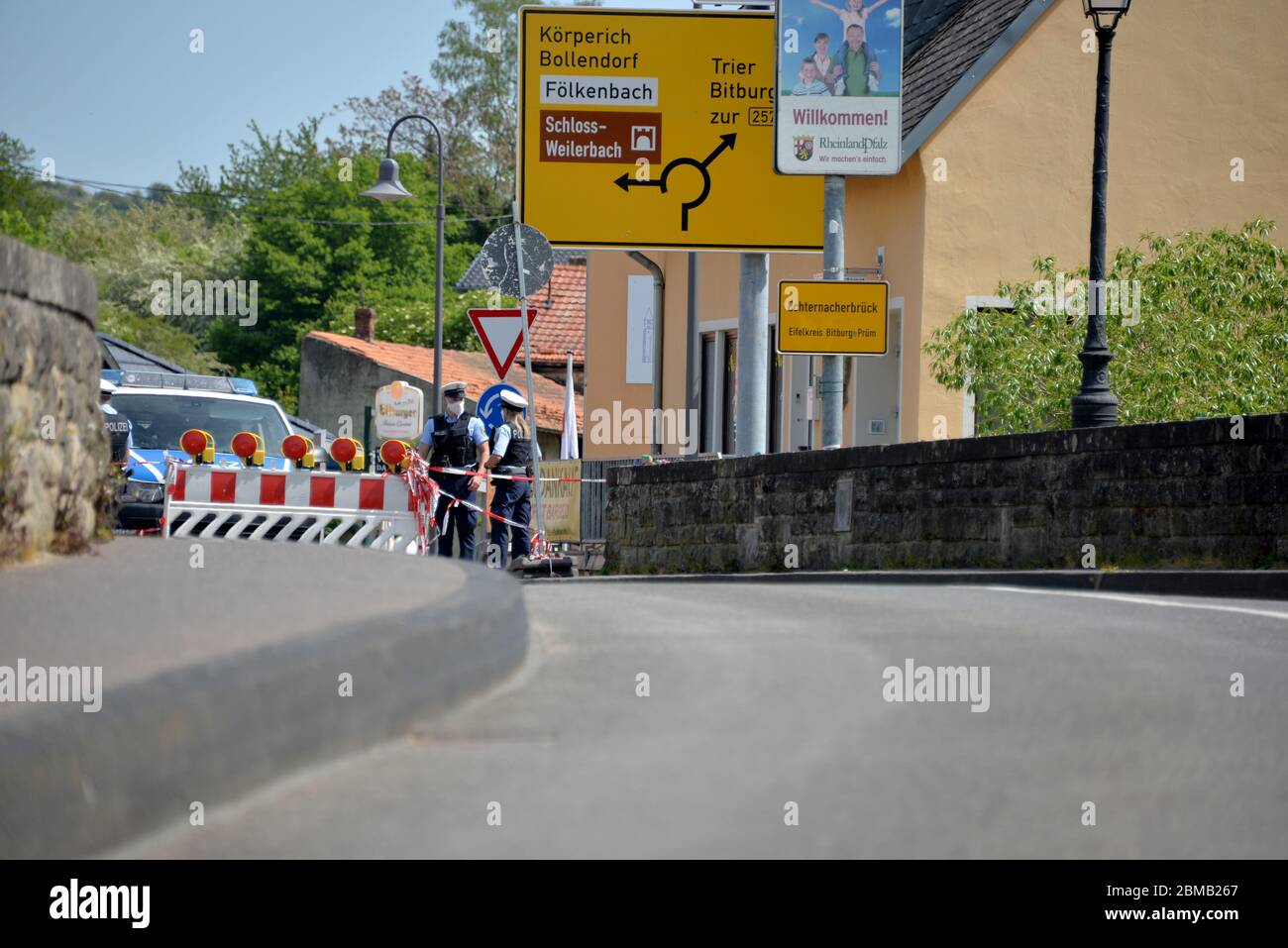 Echternach, Lussemburgo. 8 maggio 2020. Una barriera si trova sul lato lussemburghese del ponte di confine con la Germania. Sullo sfondo, i poliziotti tedeschi stanno assicurando la frontiera contro l'ingresso non autorizzato in Germania. A Echternach, i rappresentanti del consiglio comunale di Echternach e del distretto di Eifel Bitburg-Prüm hanno protestato contro la chiusura del confine tra Lussemburgo e Germania. Credit: Harald Tittel/dpa/Alamy Live News Foto Stock