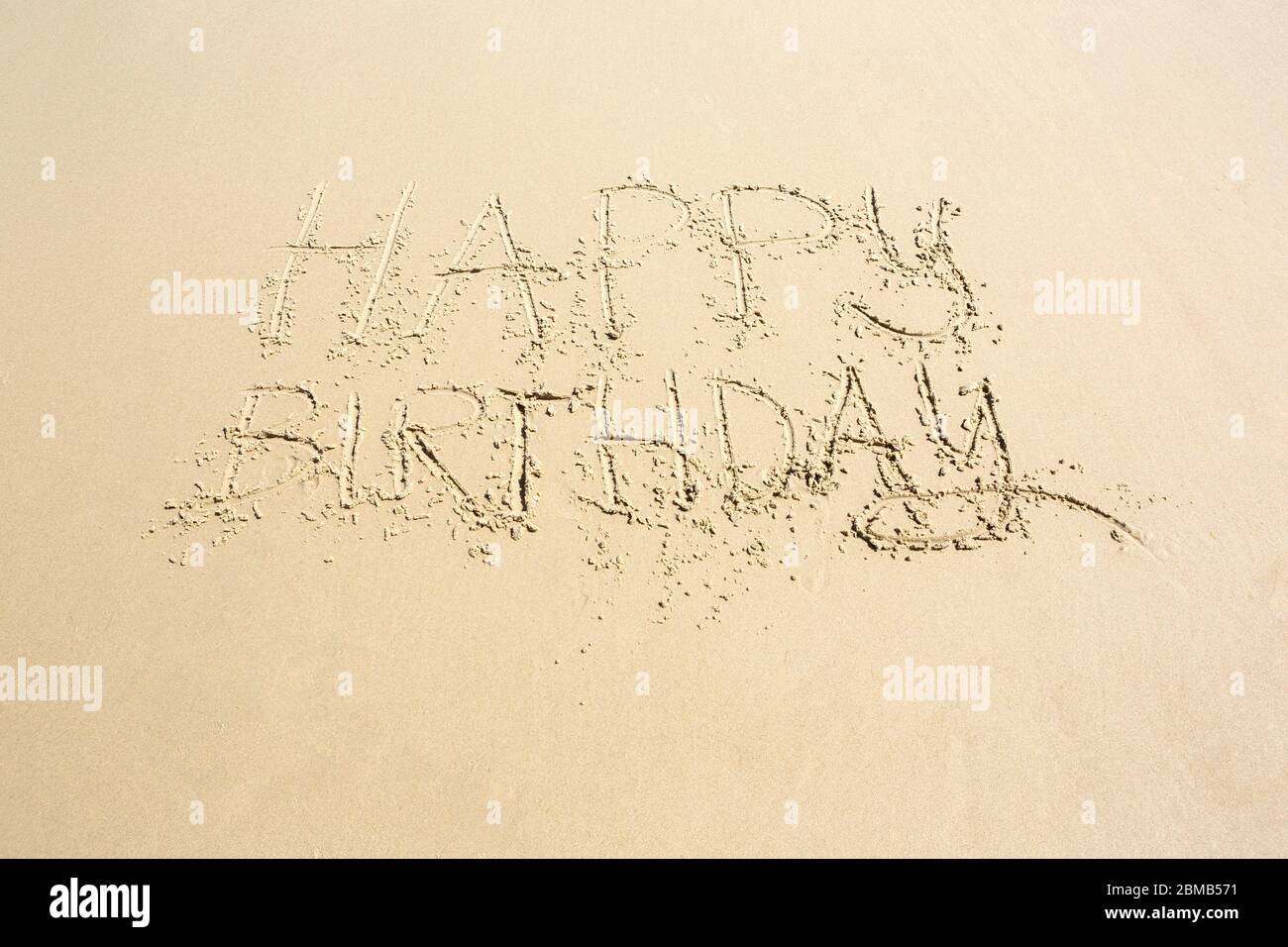 Buona mano di compleanno scritta su sabbia bagnata con spazio copia sotto in un'immagine concettuale Foto Stock
