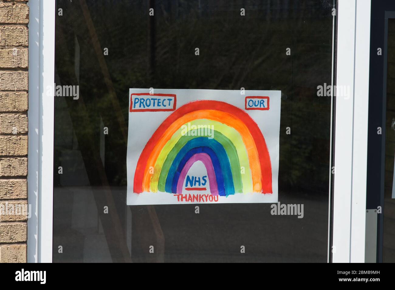 Disegno di un segno arcobaleno in finestra dicendo proteggere il nostro NHS grazie - covid19 Covid-19 coronavirus NHS appiattire la curva sociale di distanza blocco UK Foto Stock