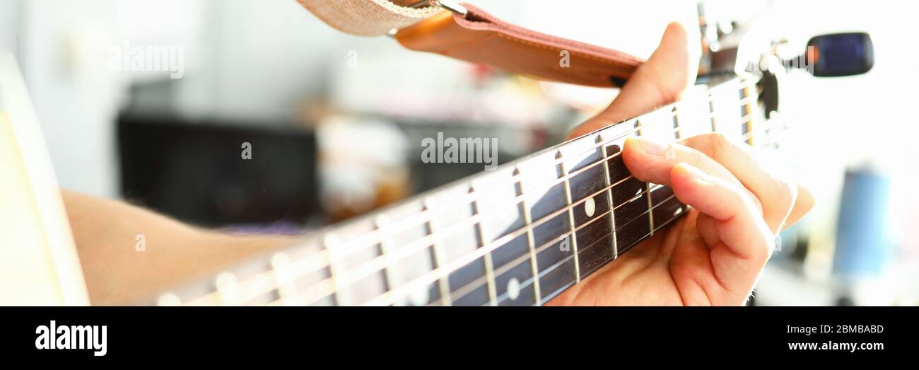 L'uomo suona la chitarra, la mano maschile tiene la chitarra al collo Foto Stock