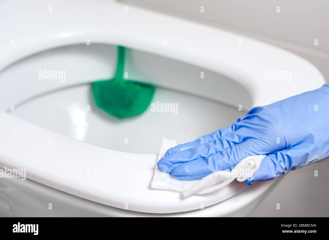 Pulire con guanti chirurgici il contenitore del water con salviette disinfettanti bagnate. Prevenzione della diffusione di batteri e coronavirus . Foto Stock