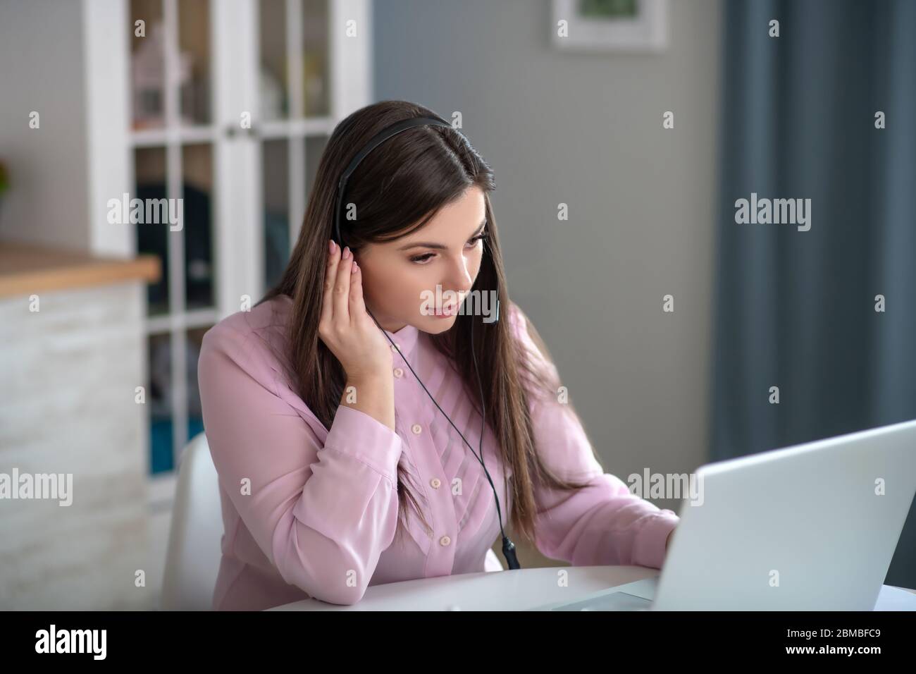 Giovane donna in una blusa rosa che ha una chiamata e che ascolta con attenzione Foto Stock