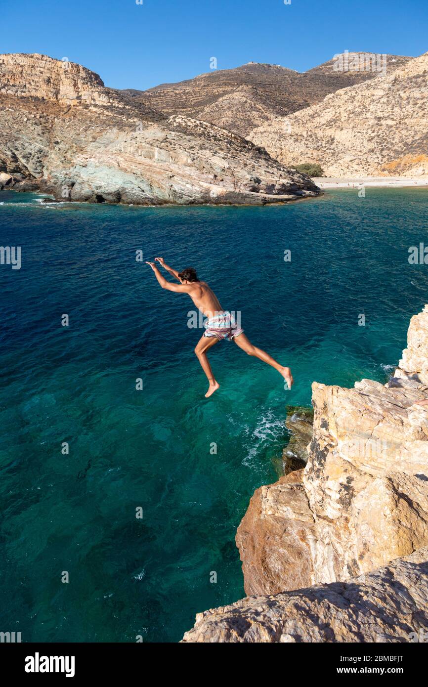 Un uomo che salta da una roccia nel mare vicino a Livadaki Beach, Folegandros, Cicladi, Grecia Foto Stock