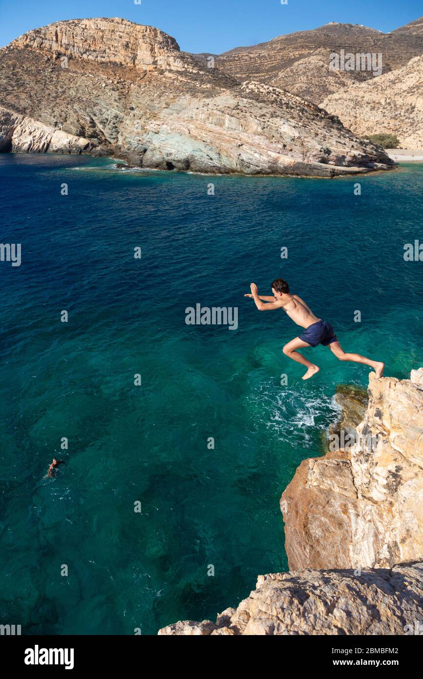 Un uomo che salta da una roccia nel mare vicino a Livadaki Beach, Folegandros, Cicladi, Grecia Foto Stock