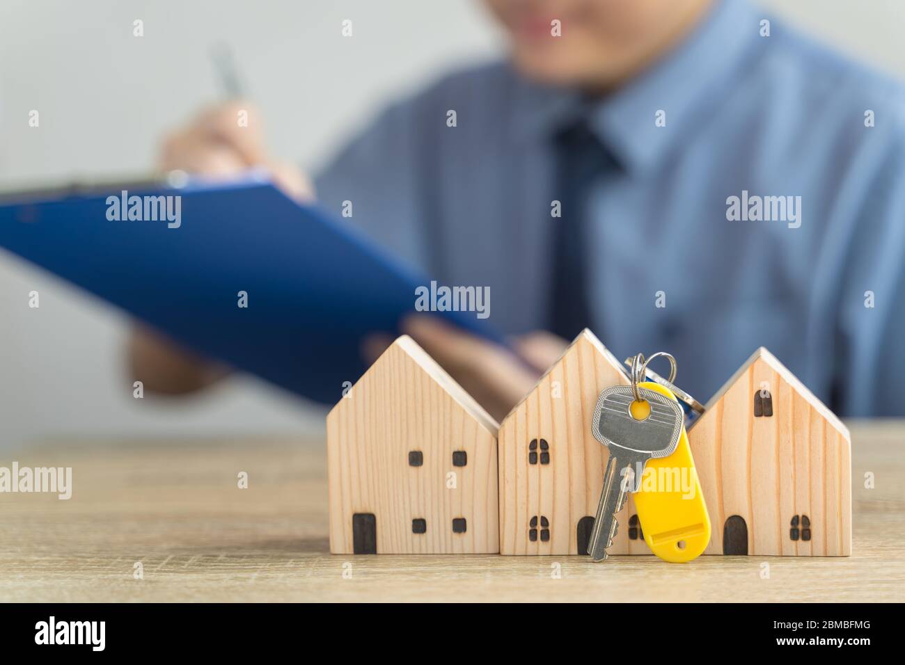 Casa modello di legno e chiave in bene immobile , venditore o acquirente , concetto di prestito con blur dipendente prestito o realtor che sta controllando i dettagli sulla vendita di Foto Stock