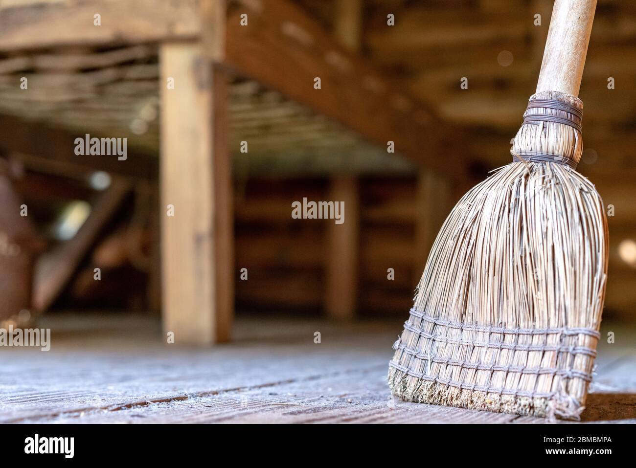 Una scopa di legno seduta su un pavimento polveroso. Foto Stock
