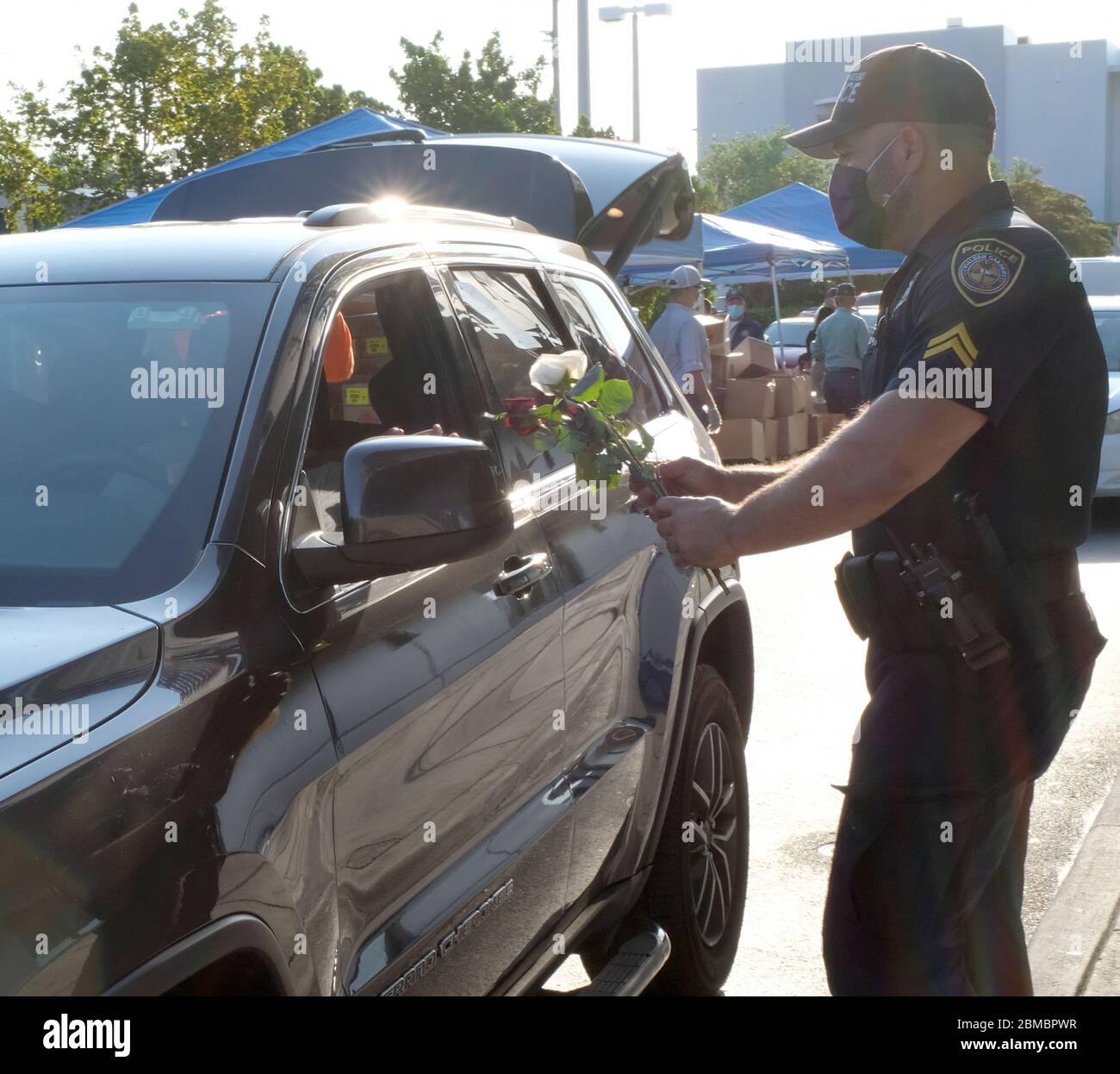 Hialeah Gardens, Stati Uniti. 8 maggio 2020. Gli ufficiali della polizia di Hialeah Gardens distribuiscono i fiori per la giornata della madre ai conducenti in veicoli che si allineano per una distribuzione del cibo drive-thru sponsorizzata dalla Master Academy Charter Middle/High School durante la pandemia COVID-19 in Florida il Venerdì, 8 maggio 2020. La distribuzione di cibo alle prime 500 auto è iniziata alle 8 e alle 8:30 sono state effettuate quasi 240 operazioni di manutenzione. Foto di Gary i Rothstein/UPI Credit: UPI/Alamy Live News Foto Stock