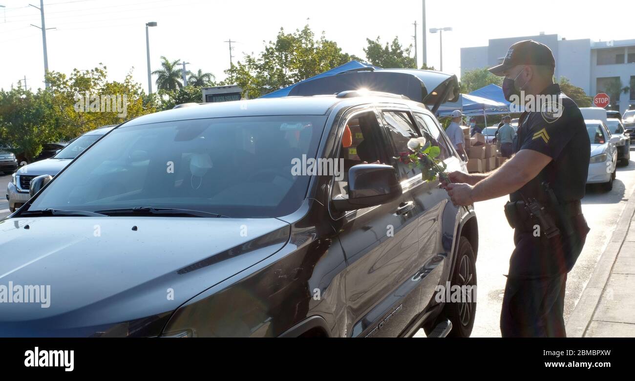 Hialeah Gardens, Stati Uniti. 8 maggio 2020. Gli ufficiali della polizia di Hialeah Gardens distribuiscono i fiori per la giornata della madre ai conducenti in veicoli che si allineano per una distribuzione del cibo drive-thru sponsorizzata dalla Master Academy Charter Middle/High School durante la pandemia COVID-19 in Florida il Venerdì, 8 maggio 2020. La distribuzione di cibo alle prime 500 auto è iniziata alle 8 e alle 8:30 sono state effettuate quasi 240 operazioni di manutenzione. Foto di Gary i Rothstein/UPI Credit: UPI/Alamy Live News Foto Stock