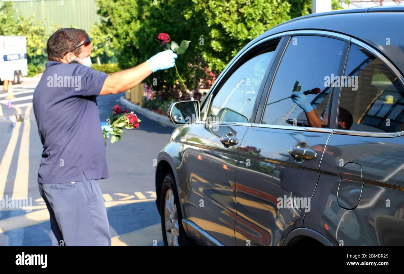 Hialeah Gardens, Stati Uniti. 8 maggio 2020. Gli ufficiali della polizia di Hialeah Gardens distribuiscono i fiori per la giornata della madre ai conducenti in veicoli che si allineano per una distribuzione del cibo drive-thru sponsorizzata dalla Master Academy Charter Middle/High School durante la pandemia COVID-19 in Florida il Venerdì, 8 maggio 2020. La distribuzione di cibo alle prime 500 auto è iniziata alle 8 e alle 8:30 sono state effettuate quasi 240 operazioni di manutenzione. Foto di Gary i Rothstein/UPI Credit: UPI/Alamy Live News Foto Stock