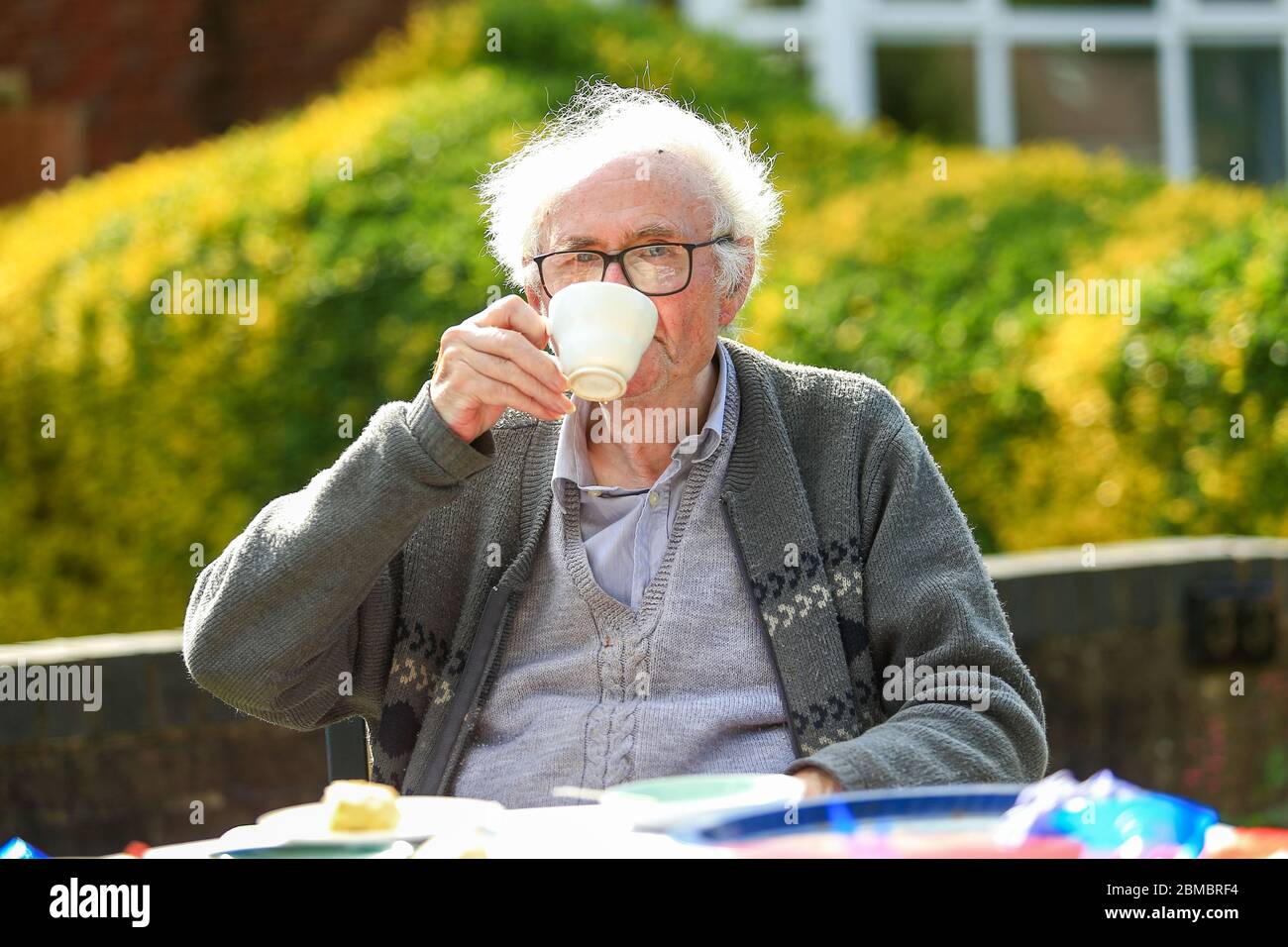 Halesowen, West Midlands, Regno Unito. 8 maggio 2020. Un anziano Signore gode di una tazza di tè molto inglese fuori dalla sua casa il giorno 75 del VE ad Halesowen, Midlands occidentali. Credit: Peter Lopeman/Alamy Live News Foto Stock
