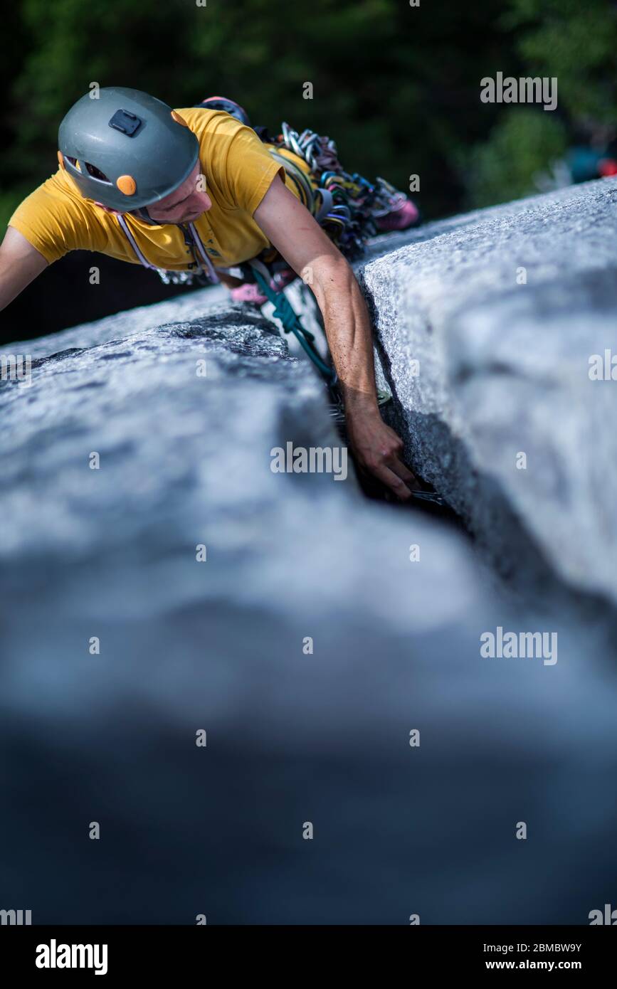 Uomo che posiziona la protezione mentre la roccia di piombo sale grande crepa su granito Foto Stock