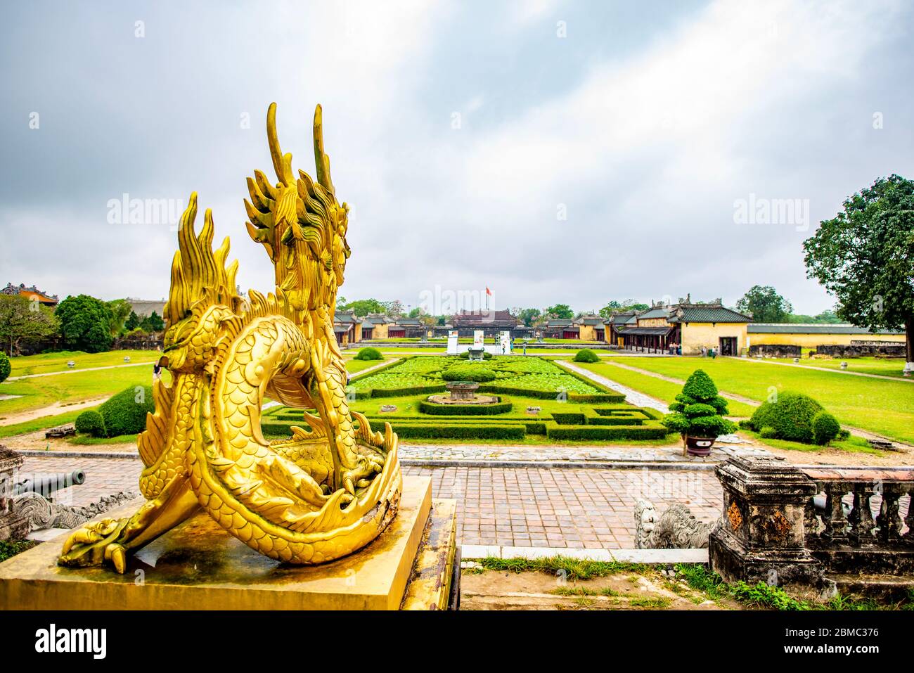 Hue, Vietnam - 15 aprile 2018: Drago d'oro che domina la cittadella di Hue porta principale con pochissimi turisti, e un cielo coperto Foto Stock
