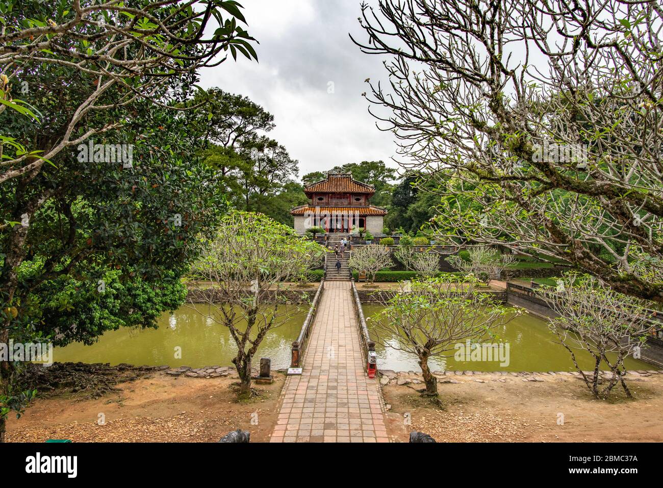 Hue, Vietnam - 16 aprile 2018: Uno dei padiglioni della Tomba Minh Mang con pochissimi turisti e un cielo coperto Foto Stock