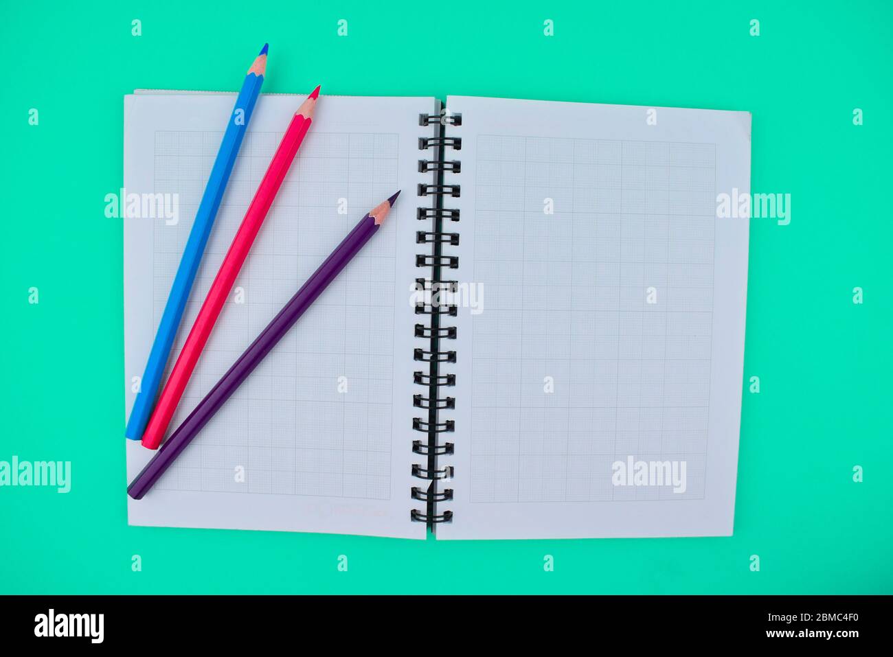 Tre diversi colori pastello a matita di legno posto sulla parte superiore di un diario aperto di carta nota Foto Stock