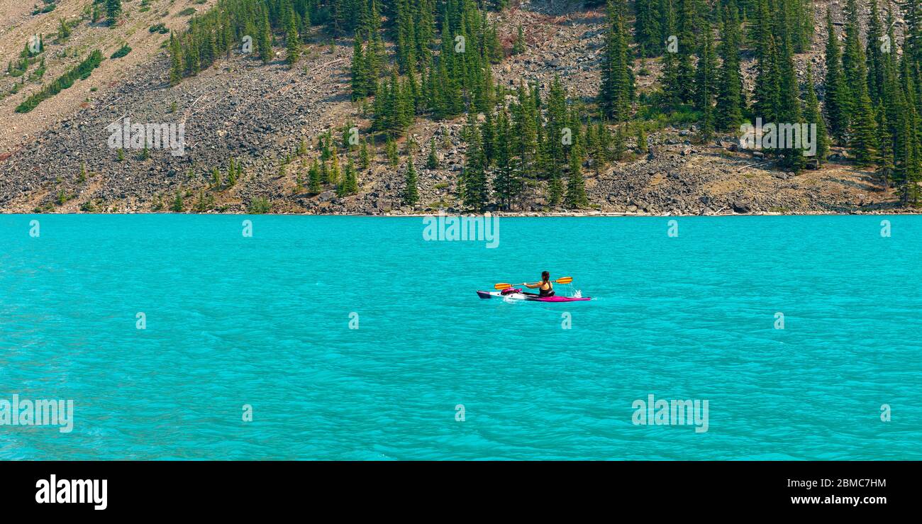 Panorama di una donna irriconoscibile fare kayak sul lago Moraine in estate, Banff parco nazionale, Alberta, Canada. Foto Stock