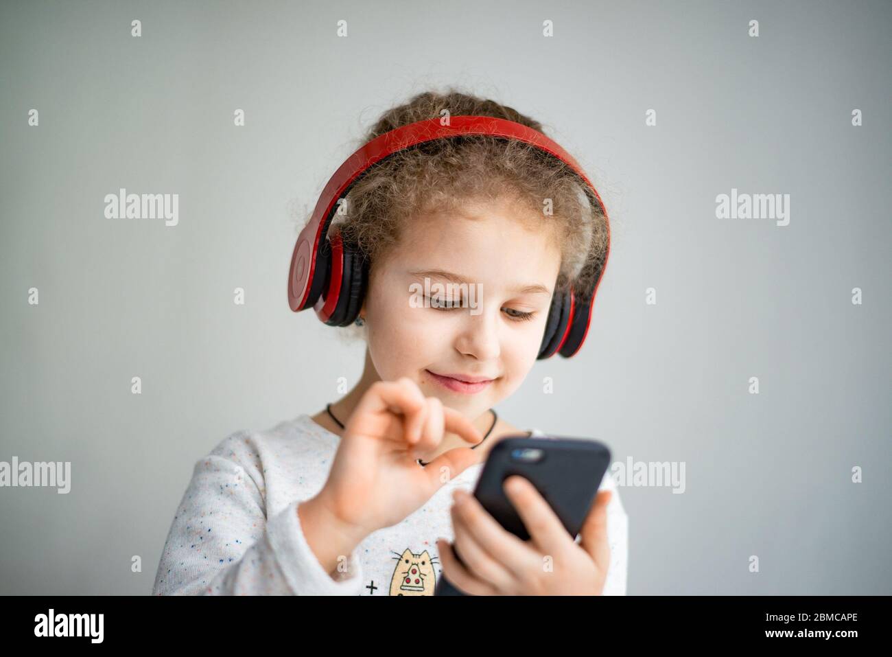 bambina in cuffie rosse con telefono Foto Stock