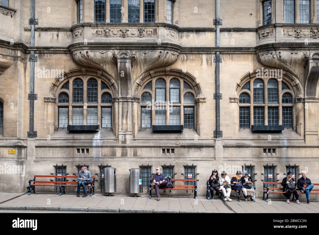 Oxford Town Hall, St Aldates., costruito in stile giacobino nel 1897. Mostrato con turisti asiatici seduti om panchine davanti Foto Stock