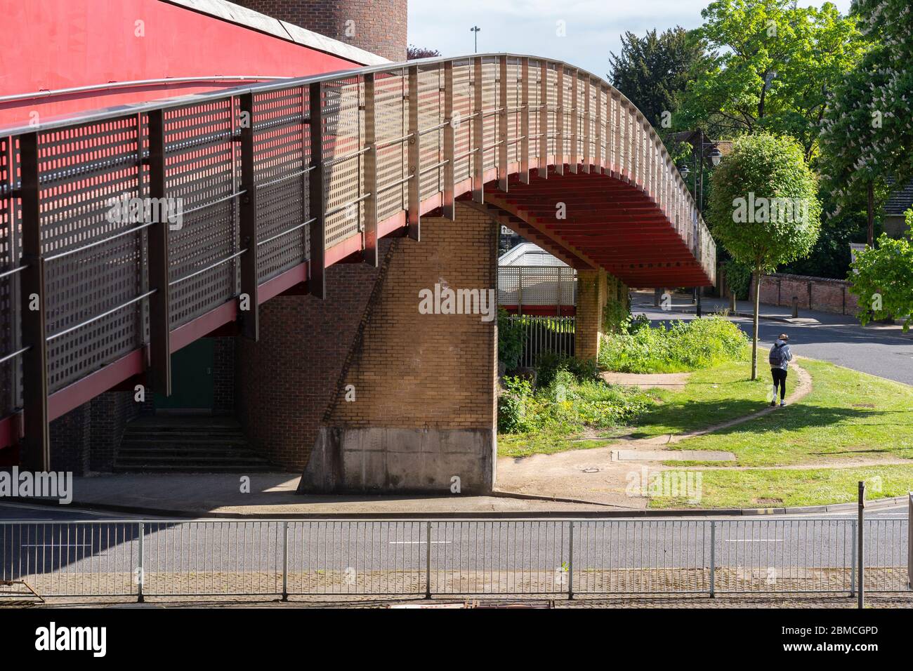 Un ponte pedonale ad arco che attraversa la strada a doppia carreggiata di Churchill Way East a Basingstoke con una persona che cammina sotto, Regno Unito Foto Stock