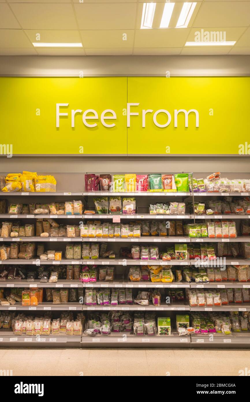 Cartello con il testo Free from - glutine, lattosio, latticini e soia libera corridoio con prodotti su scaffali in Waitrose supermercato, Basingstoke, Regno Unito Foto Stock