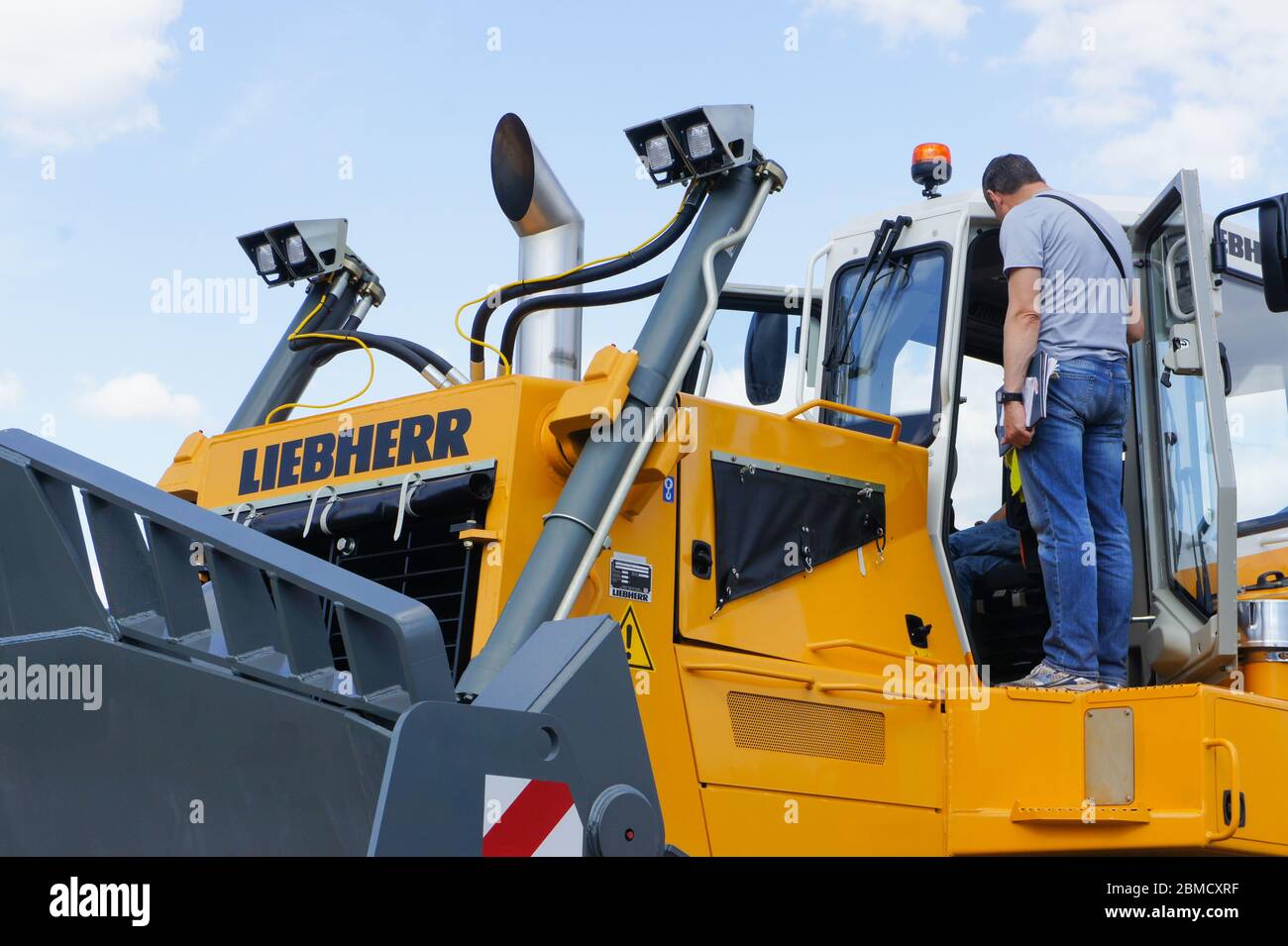 Mosca, Russia - 4 giugno 2016: Due uomini che ispezionano la cabina operatore di 50 tonn Liebherr bulldozer, passando attraverso le funzioni di base apripista. Foto Stock