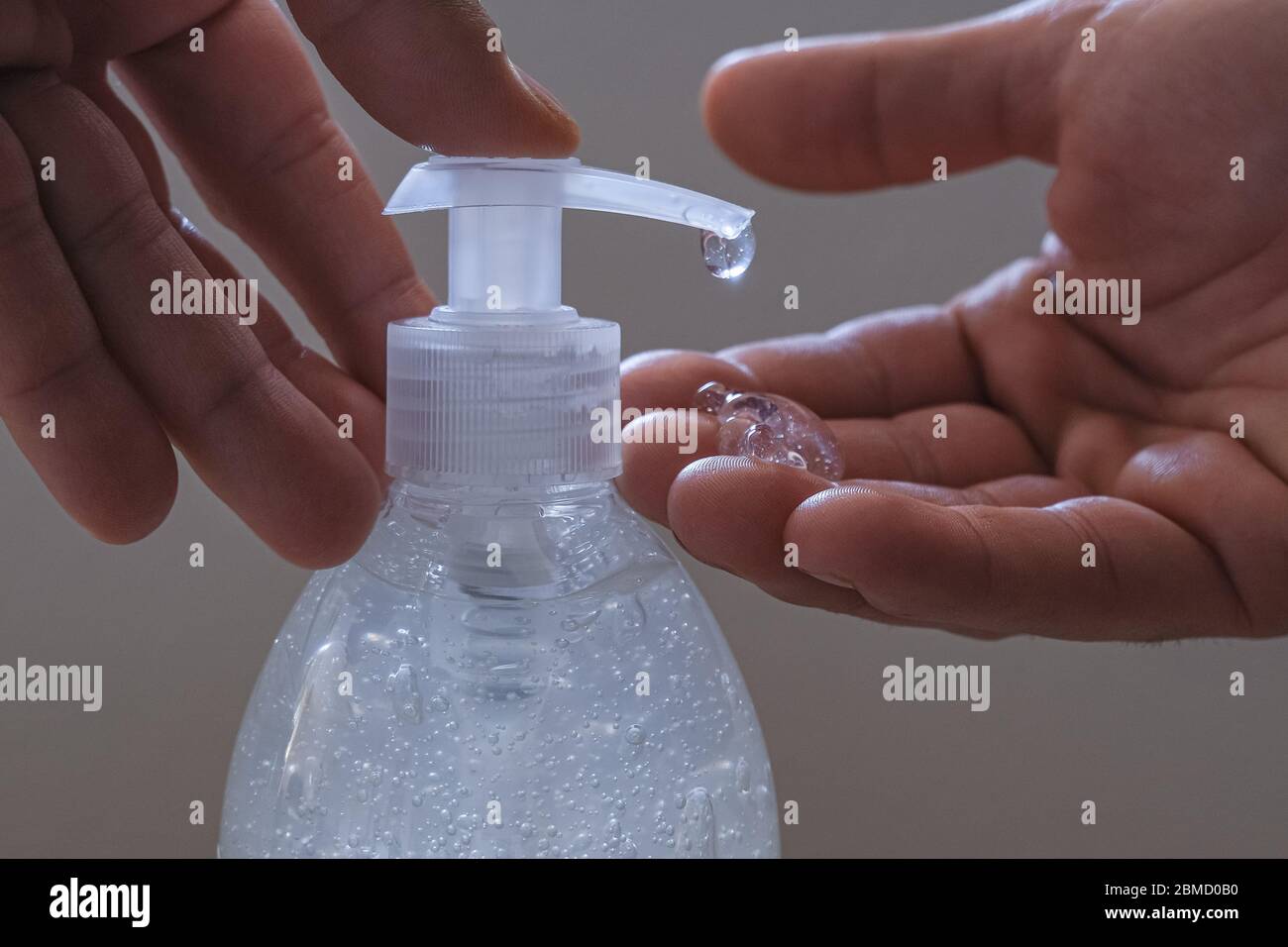 Mani di tipo mentre sanitizzano con l'alcool dispenser di igienizzatore mani, malattia del covid del virus della corona Foto Stock
