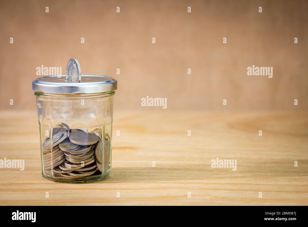 Il vaso riutilizzato ha usato per risparmiare i soldi, con la moneta che passa attraverso la fessura nel coperchio e le monete nel vaso, risparmi i soldi, riciclano, riutilizza, concetto di sparo Foto Stock