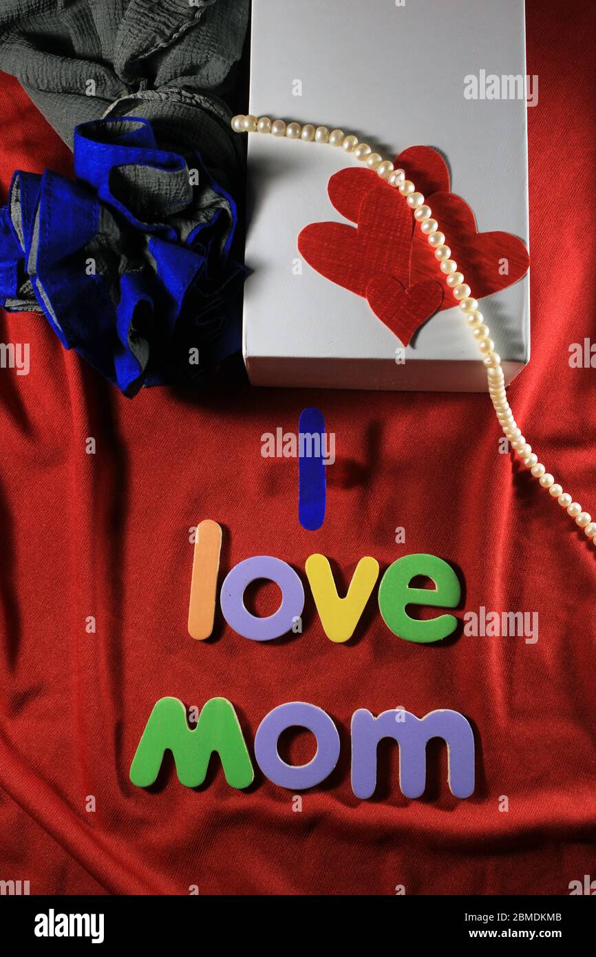 Lettere colorate con la mamma i love isolato su fondo di tessuto rosso. Amo la mamma scritta con lettere colorate e cuore rosso per la giornata delle madri. Foto Stock
