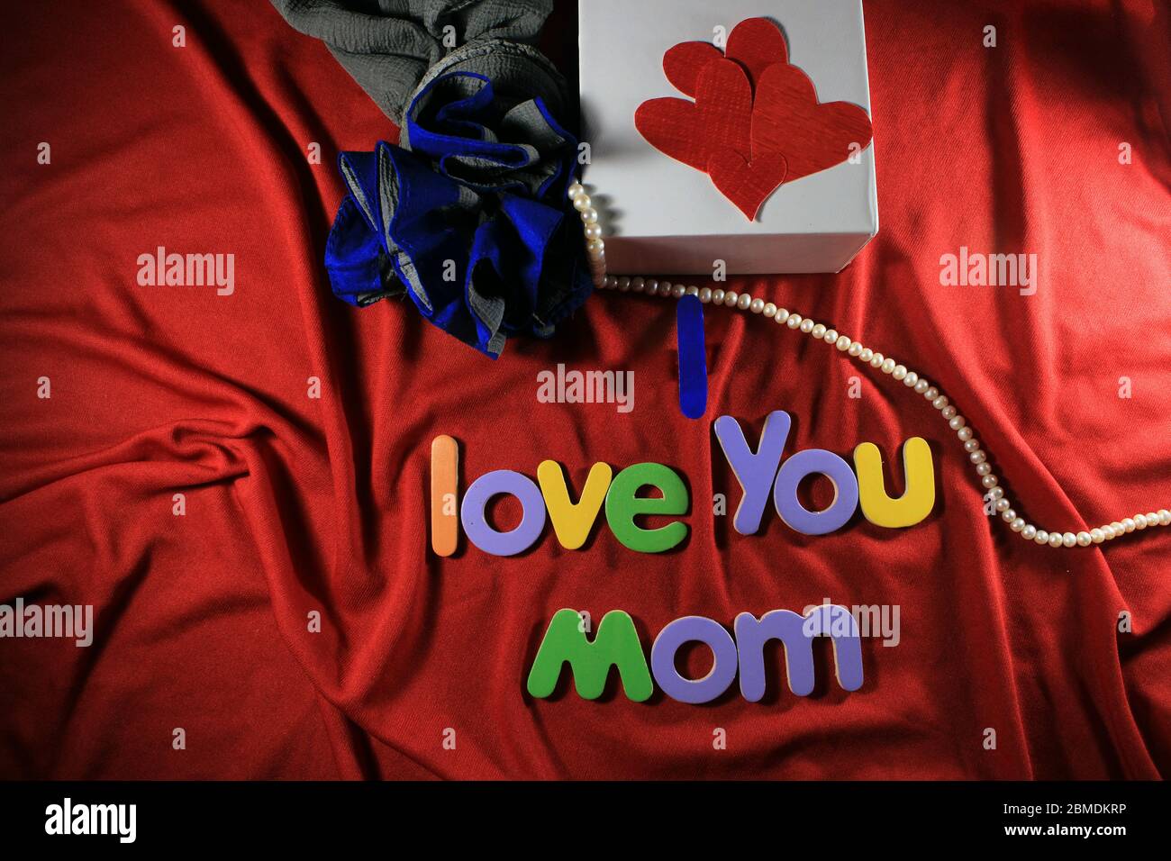 Lettere colorate con i love si mamma isolato su fondo rosso tessuto. Ti amo mamma con lettere colorate e cuore rosso per la giornata delle madri. Foto Stock