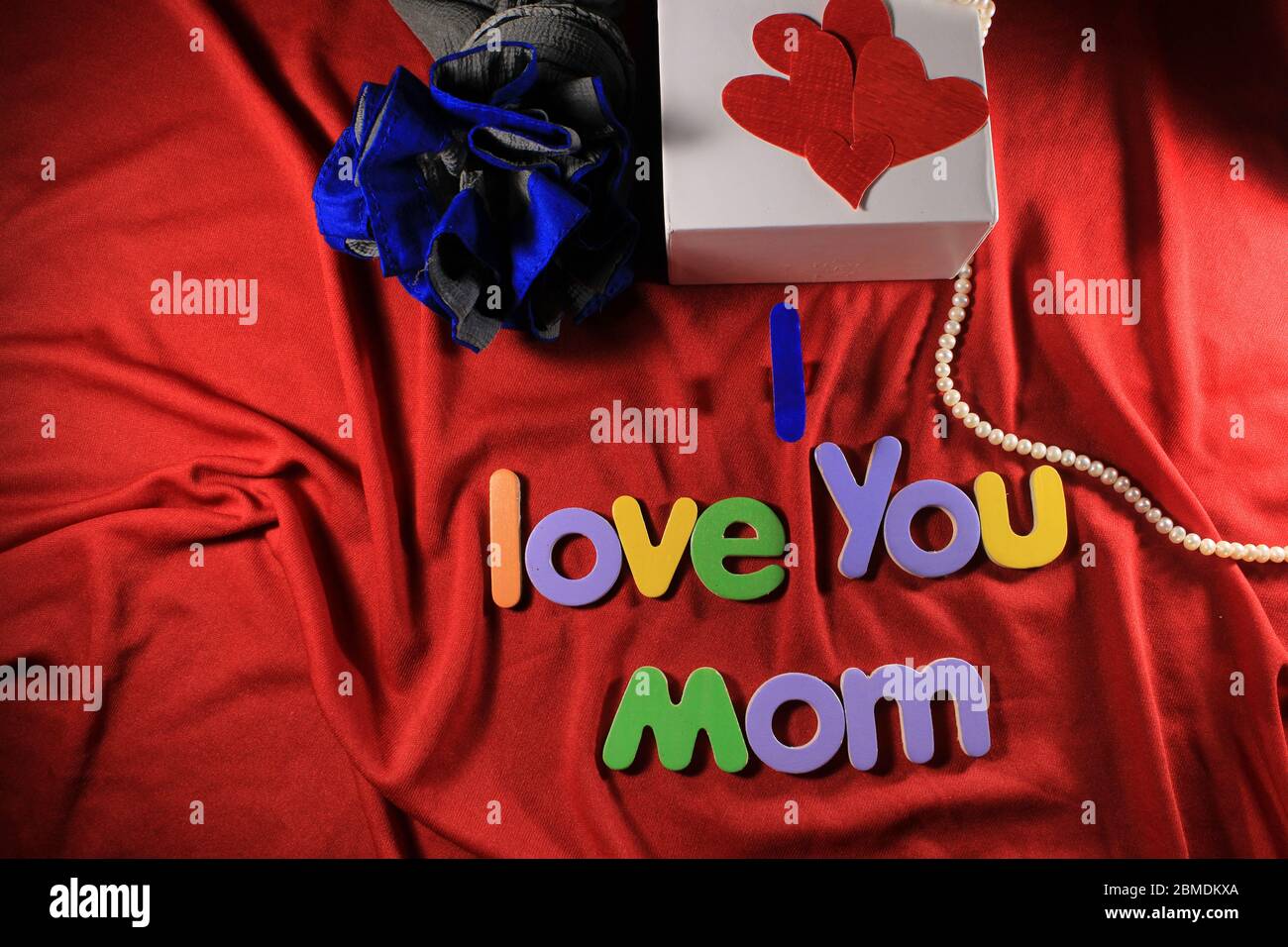 Lettere colorate con i love si mamma isolato su fondo rosso tessuto. Ti amo mamma con lettere colorate e cuore rosso per la giornata delle madri. Foto Stock