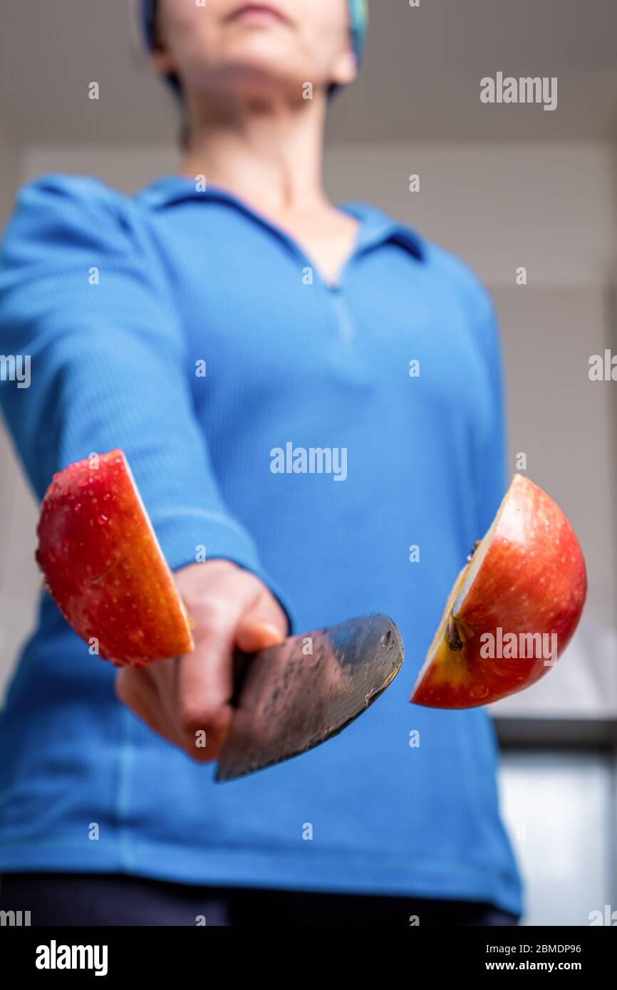 Closeup estremo della donna che taglia la mela in metà dell'aria con fuoco poco profondo Foto Stock