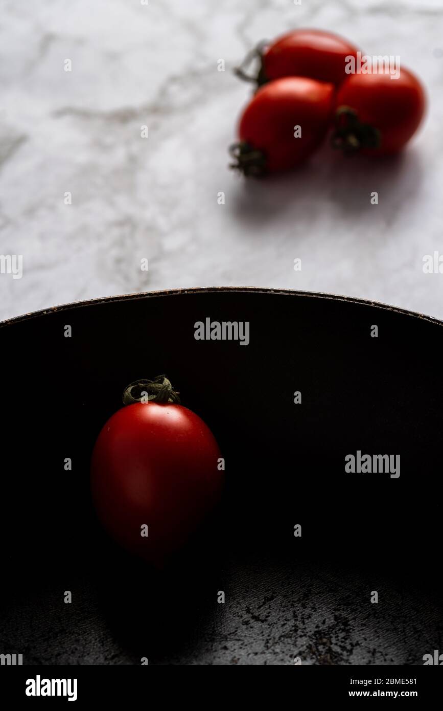 Pomodori freschi e sani rossi isolati su una teglia nera Foto Stock