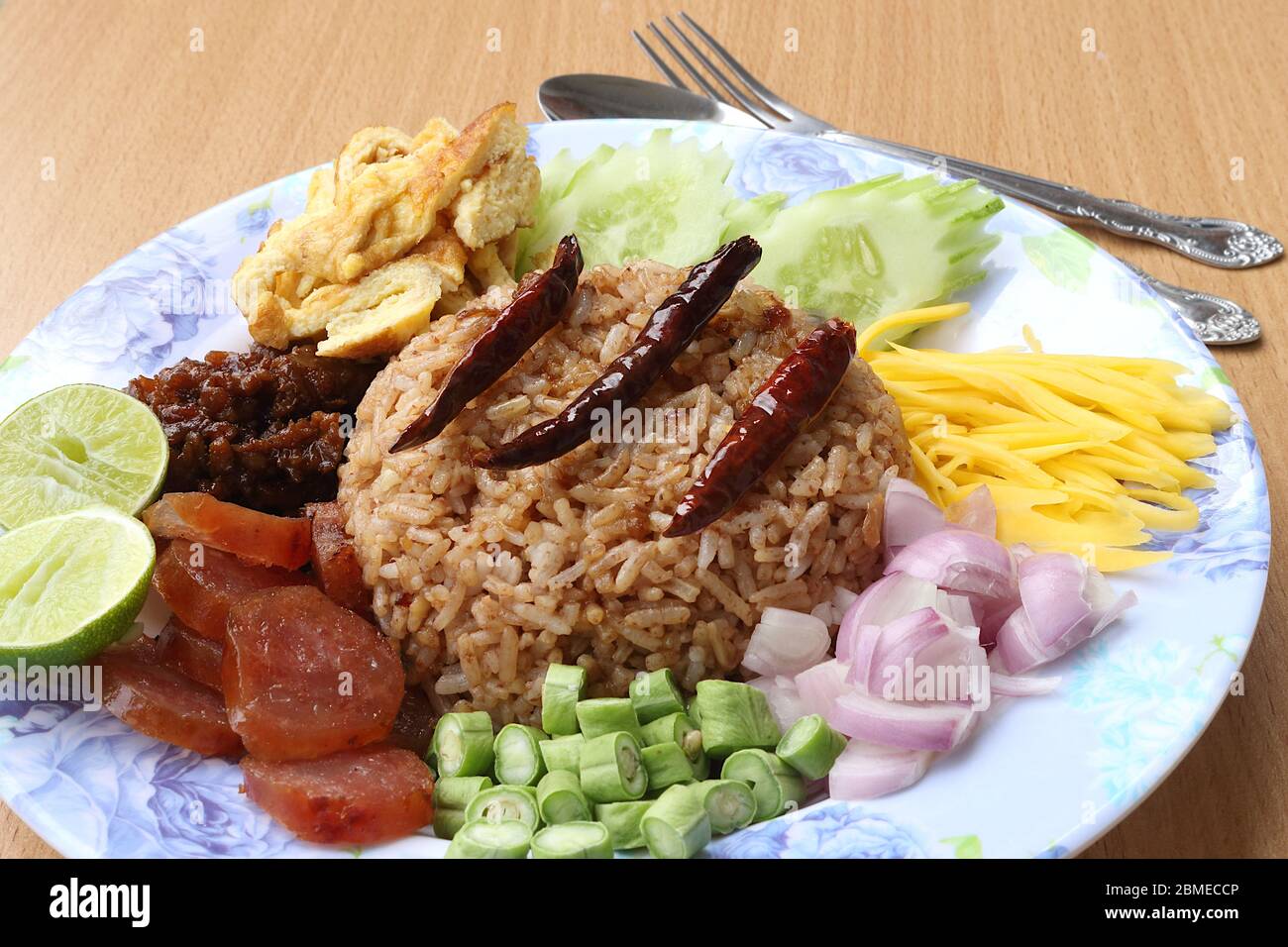 Riso misto con pasta di gamberi composta da maiale dolce, salsiccia cinese, uova fritte, fette di cetriolo, mango agrodolce, scalogno, fagiolo lungo, pepe arrosto Foto Stock