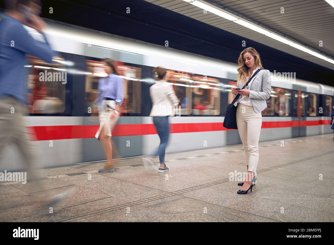 Giovane donna d'affari che aspetta la metropolitana e messaggi di testo. Foto Stock