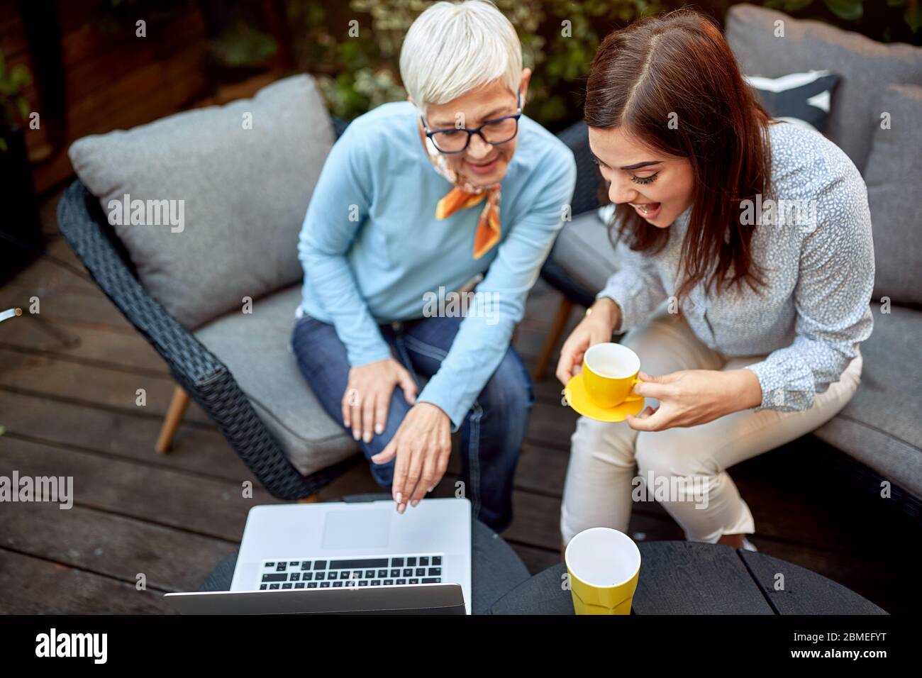 madre e figlia che guardano contenuti digitali su un notebook, sorridendo e ridendo Foto Stock