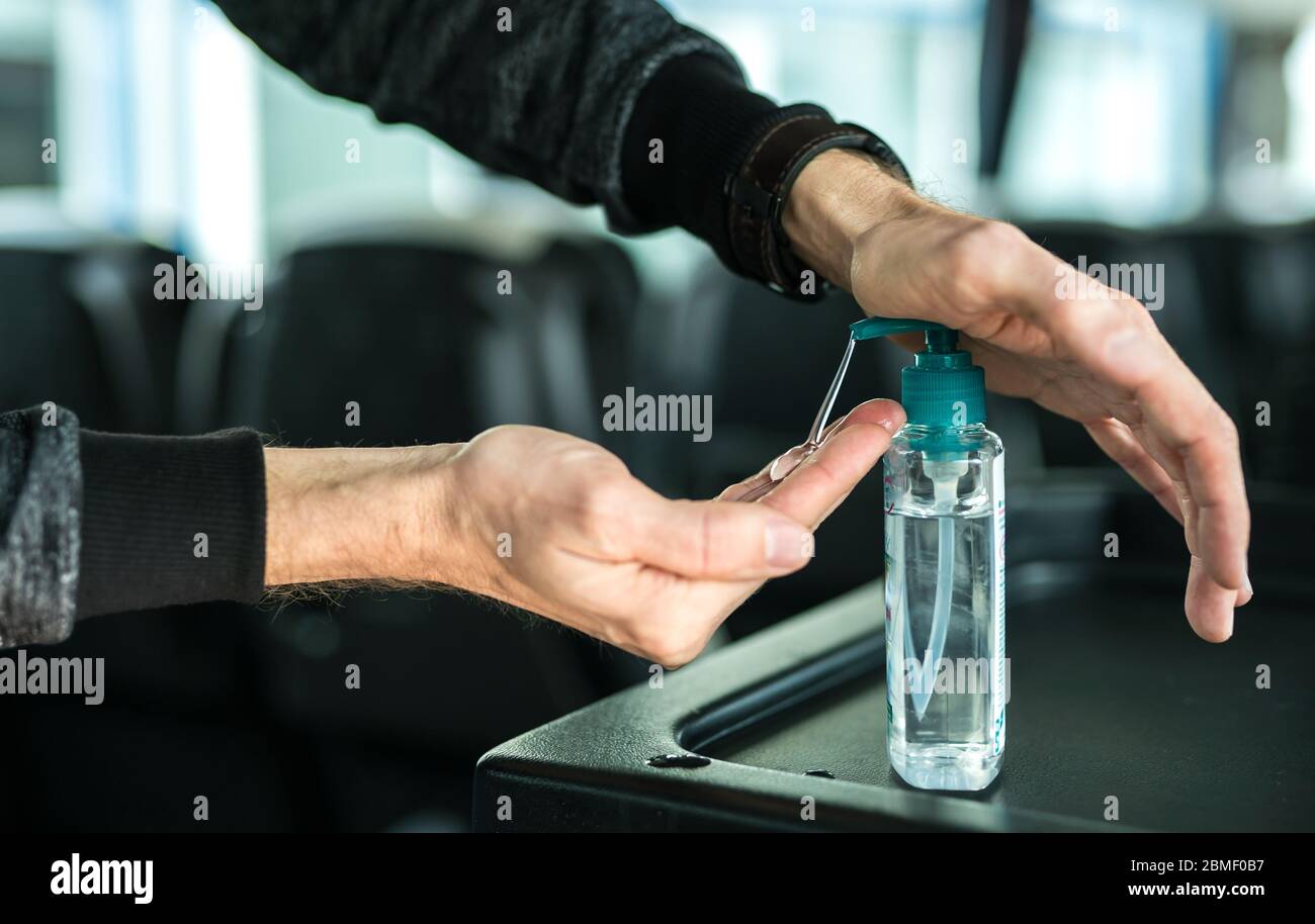 Il passeggero disinfetta la mano con l'igienizzatore sull'autobus, nel rispetto delle norme igieniche sui trasporti pubblici. Foto Stock