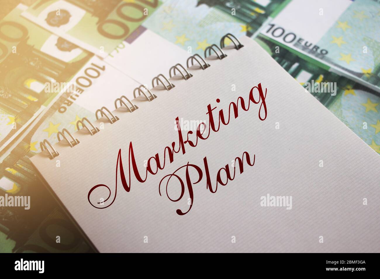 Marketing Plan parole a pagina di copybook su 100 euro fatture. Messa a fuoco selettiva. Concetto di pianificazione della gestione aziendale Foto Stock