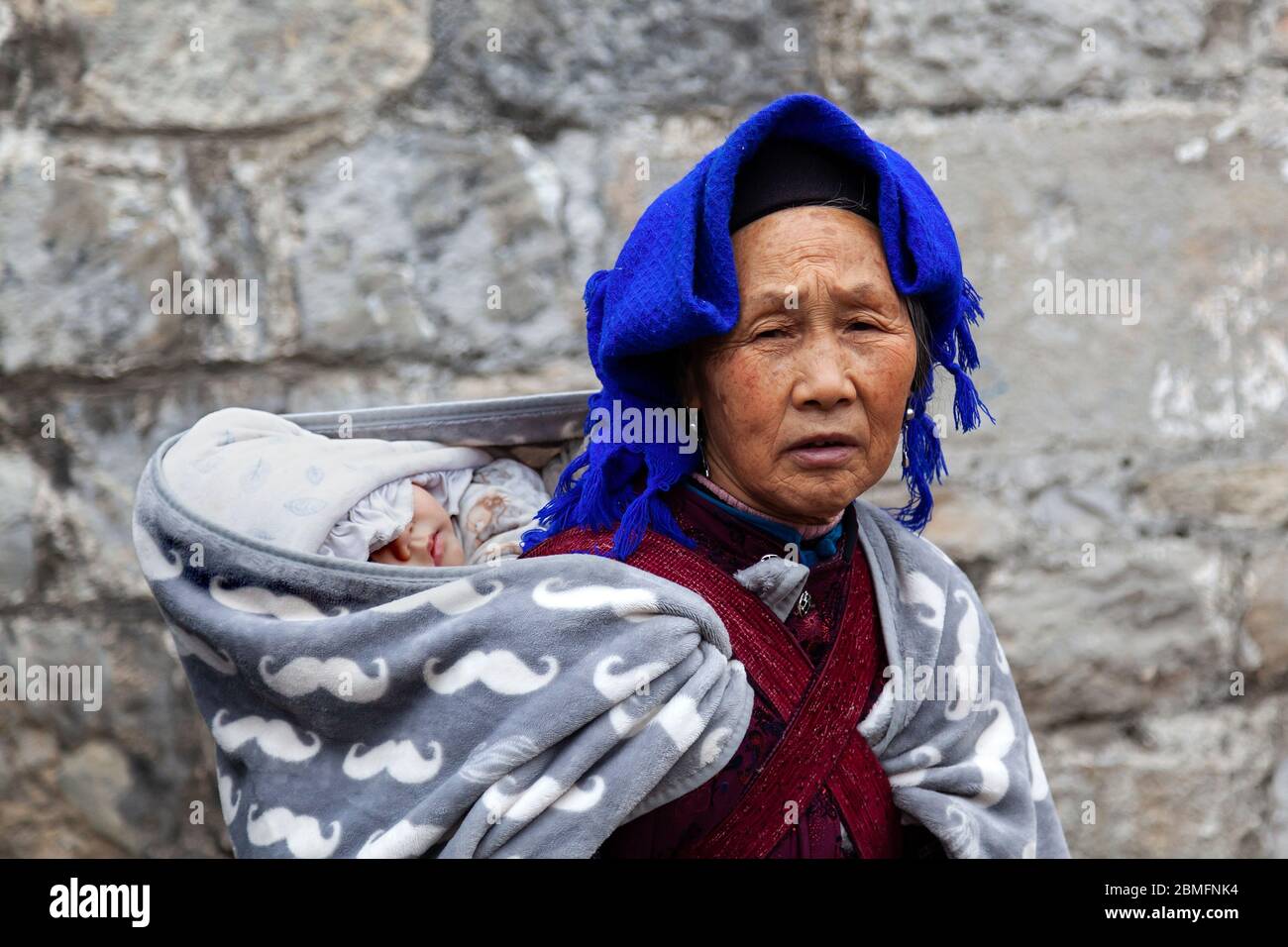 Una donna anziana che porta il nipote. Area di Anshun, provincia di Guizhou, Cina Foto Stock
