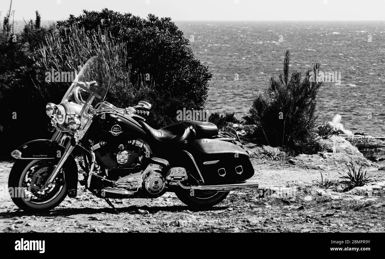 Harley Davidson bici parcheggiata con proprietario che dorme a far-end - monocromatico Foto Stock