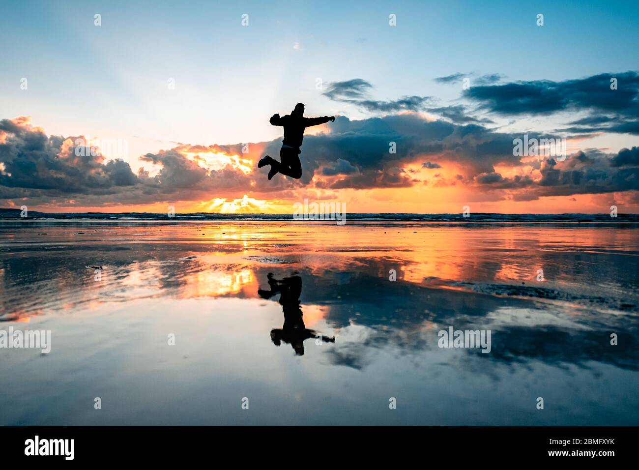 Silhouette di una persona che salta alla spiaggia di Westward ho, Devon Foto Stock