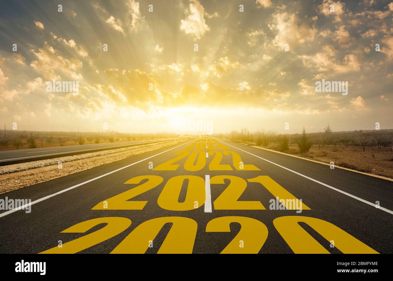 La parola 2021 scritta sulla strada statale nel mezzo di strada asfaltata vuota all'alba dorata Foto Stock