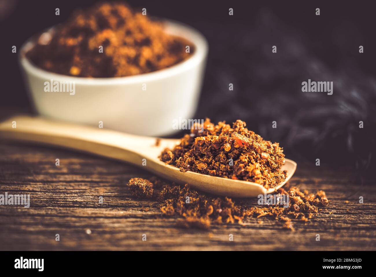 Pasta di peperoncino piccante e secca con cucchiaio di legno e fondo Foto Stock