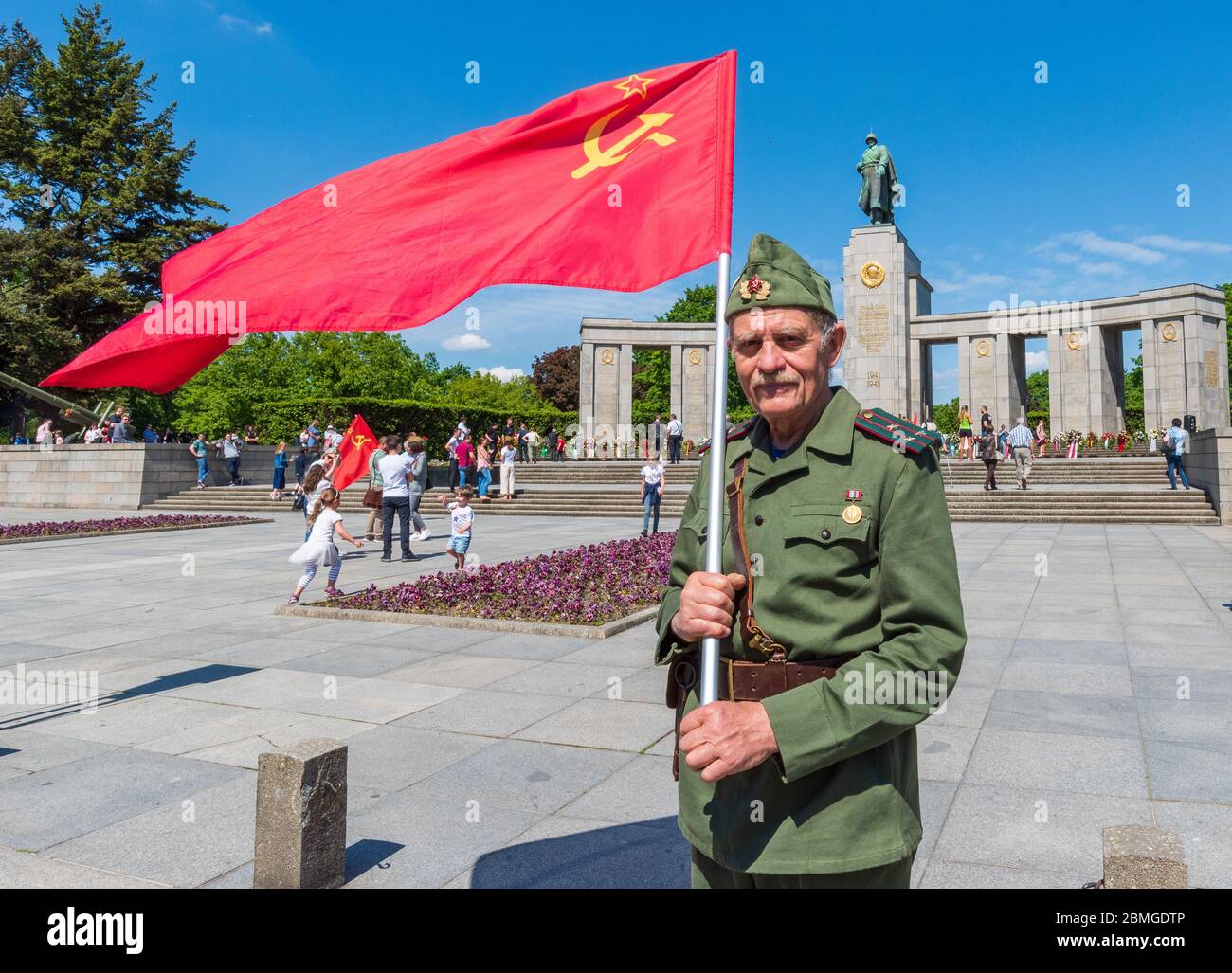 L'uomo che indossa l'uniforme della seconda guerra mondiale e porta la bandiera sovietica si trova di fronte al memoriale di guerra sovietico a Tiergarten, Berlino, per celebrare il 75° anniversario della vittoria sulla Germania nazista Foto Stock