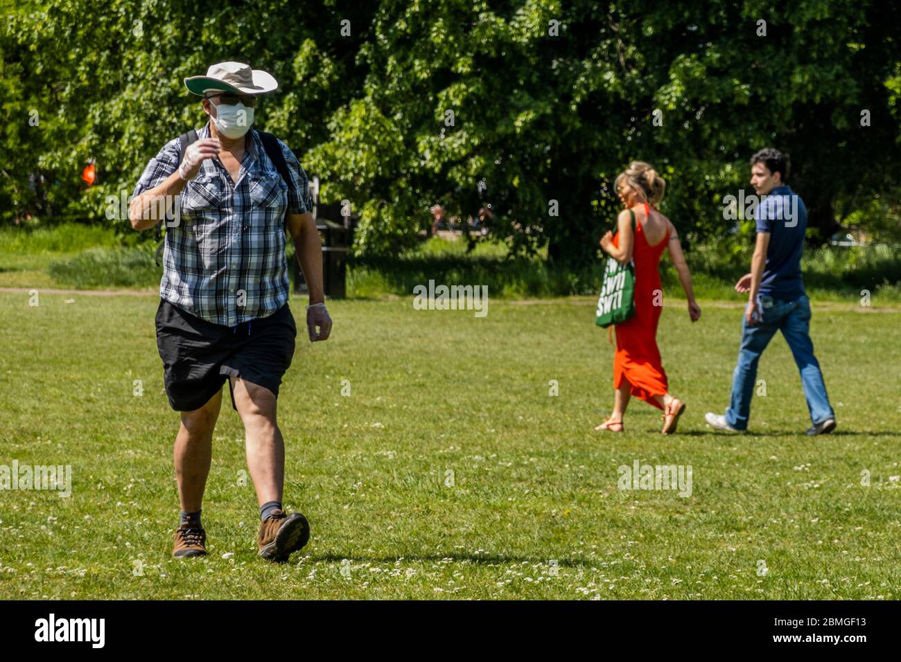Londra, Regno Unito. 9 maggio 2020. Un uomo, apparentemente inutilmente, indossa una maschera e guanti per camminare attraverso il comune. Clapham Common non è così occupato nonostante il sole sia fuori e che ora si può sedere, se solo brevemente, sulle panchine. Il blocco continua per l'epidemia di Coronavirus (Covid 19) a Londra. Credit: Guy Bell/Alamy Live News Foto Stock