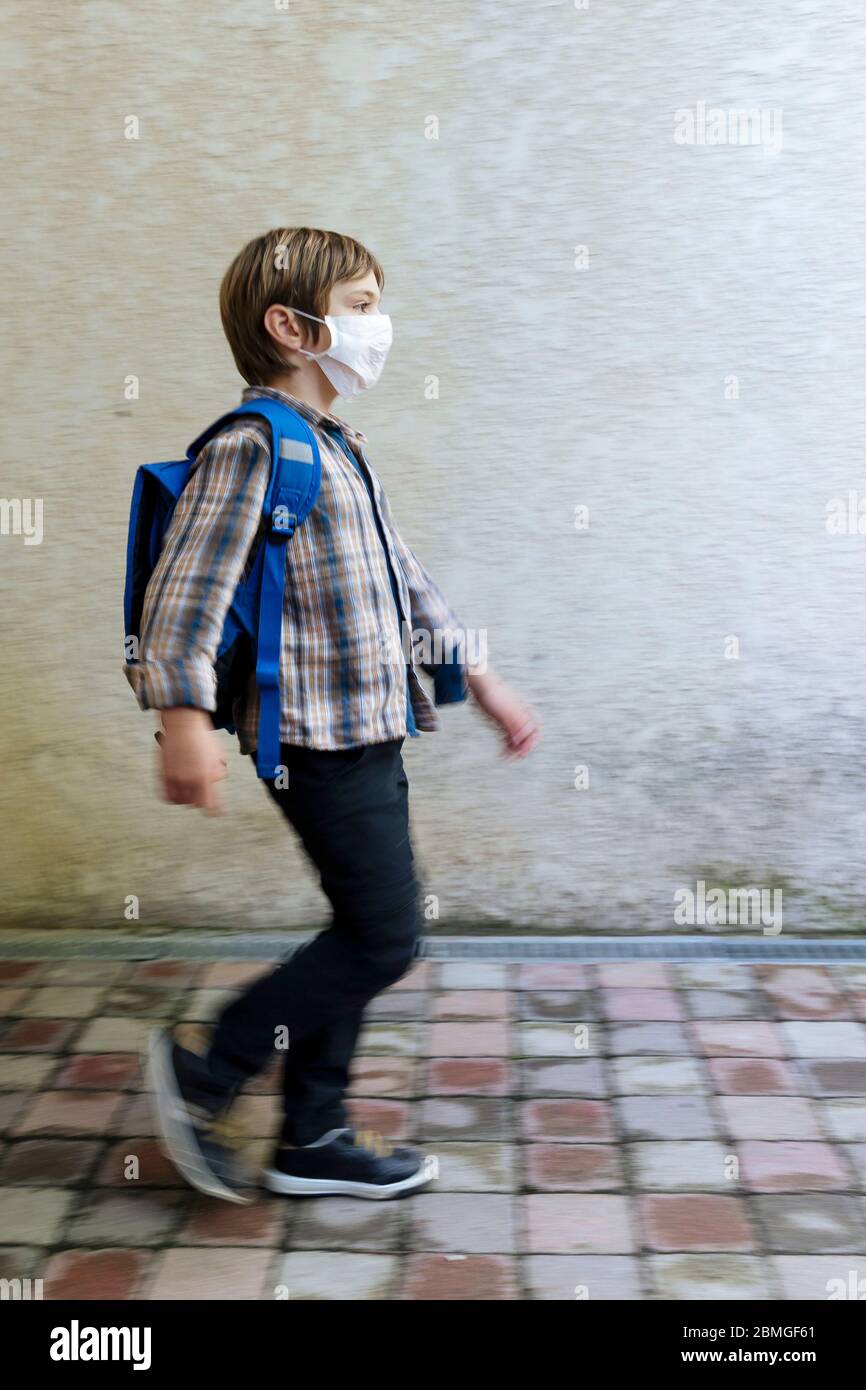 Focolaio di coronavirus, Covid-19: Illustrazione sulla riapertura delle scuole. Scolaretto che va a scuola con uno zaino e una maschera protettiva il 30 aprile, Foto Stock