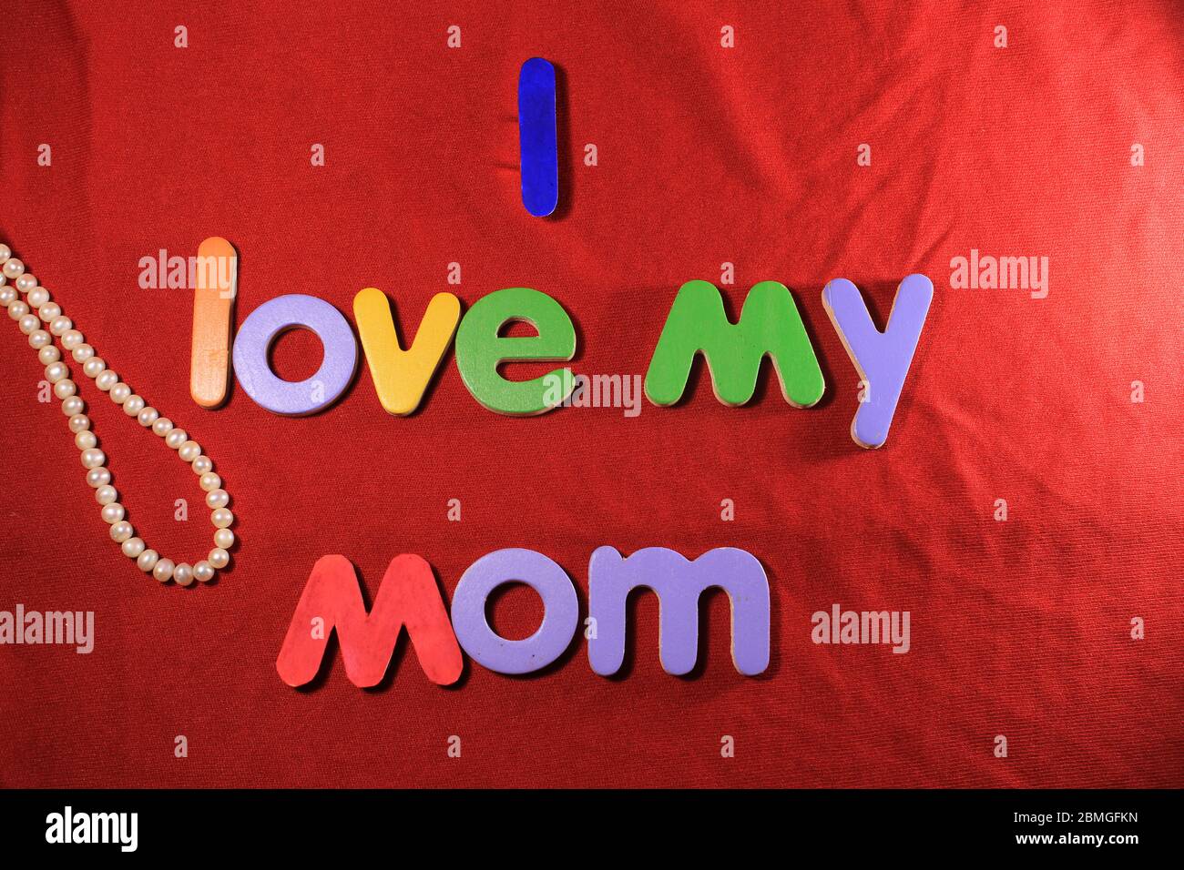 Lettere colorate con amo la mia mamma isolato su fondo di tessuto rosso. Amo la mia mamma con lettere colorate e cuore rosso per la giornata delle madri. Foto Stock
